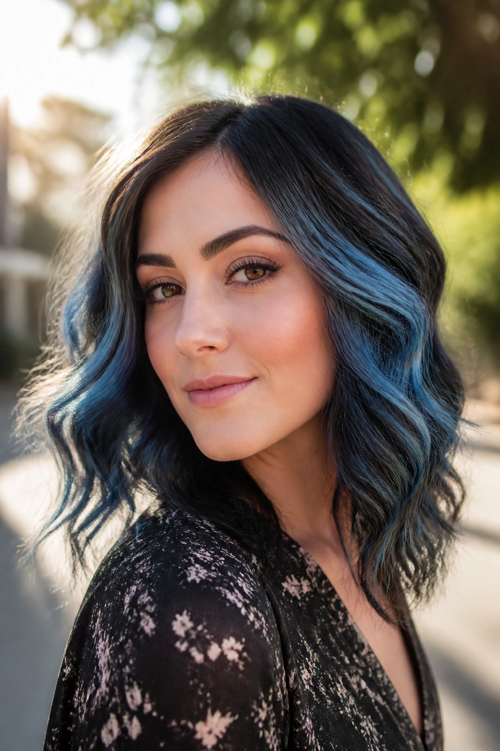 Wavy hair with denim-blue ribbons visible on both sides, sunlit outdoor setting.