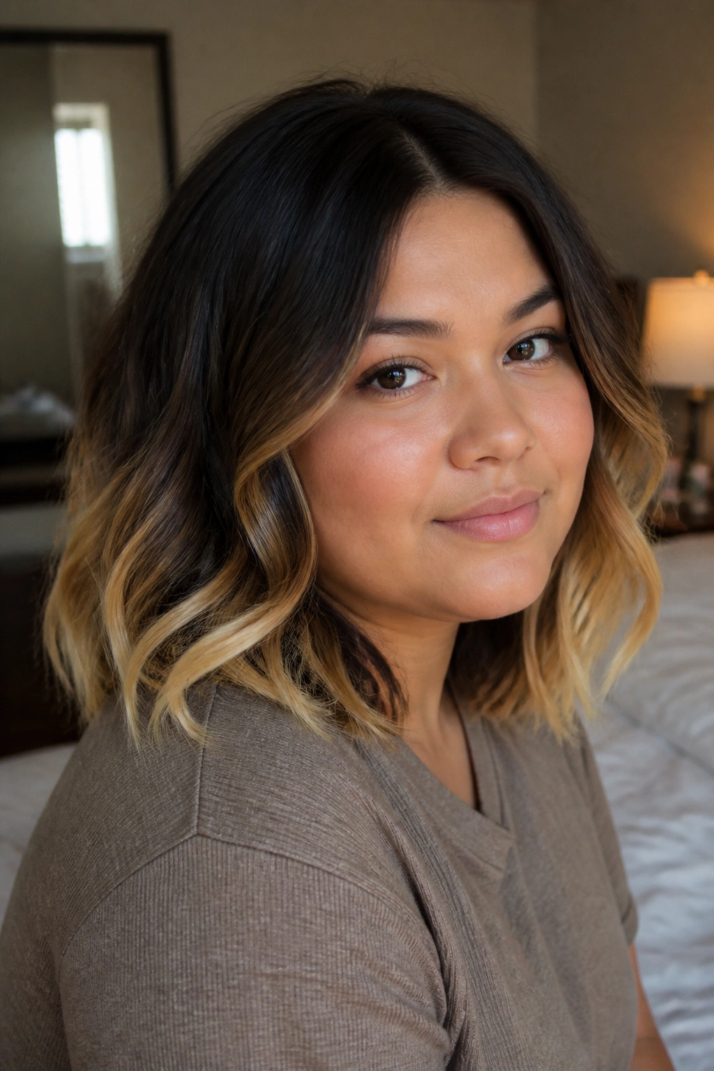 Close-up of a real woman's hair showing dip-dyed blonde ends in a warm bedroom setting
