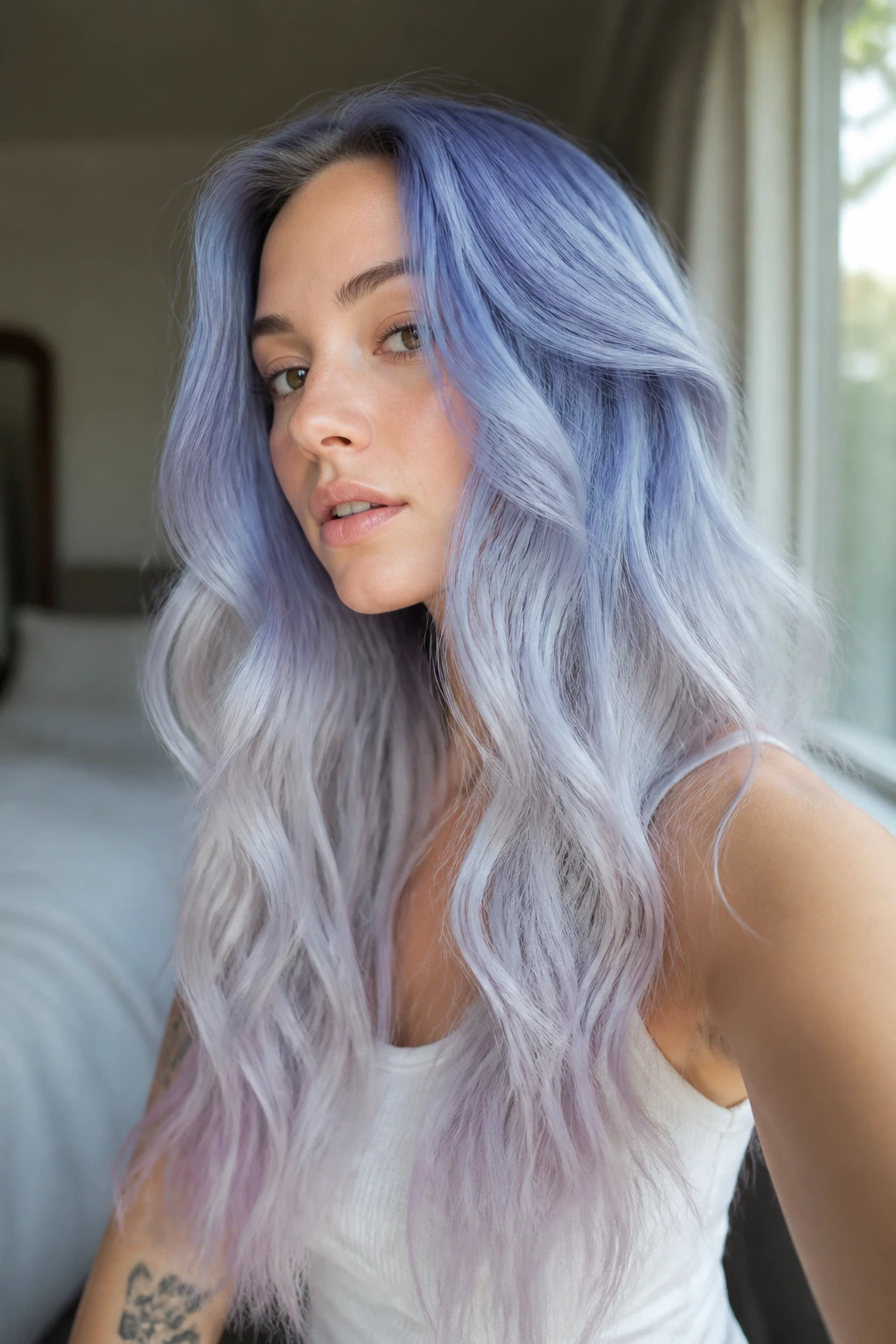 Close-up of real woman with dusty periwinkle fade on long hair by a bedroom window