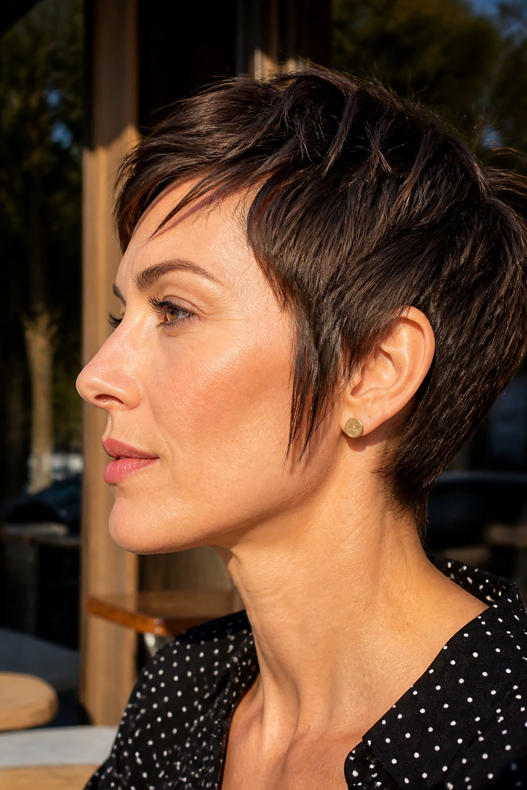 Close-up profile of a real woman with ear-length pixie and long sideburns in street light.
