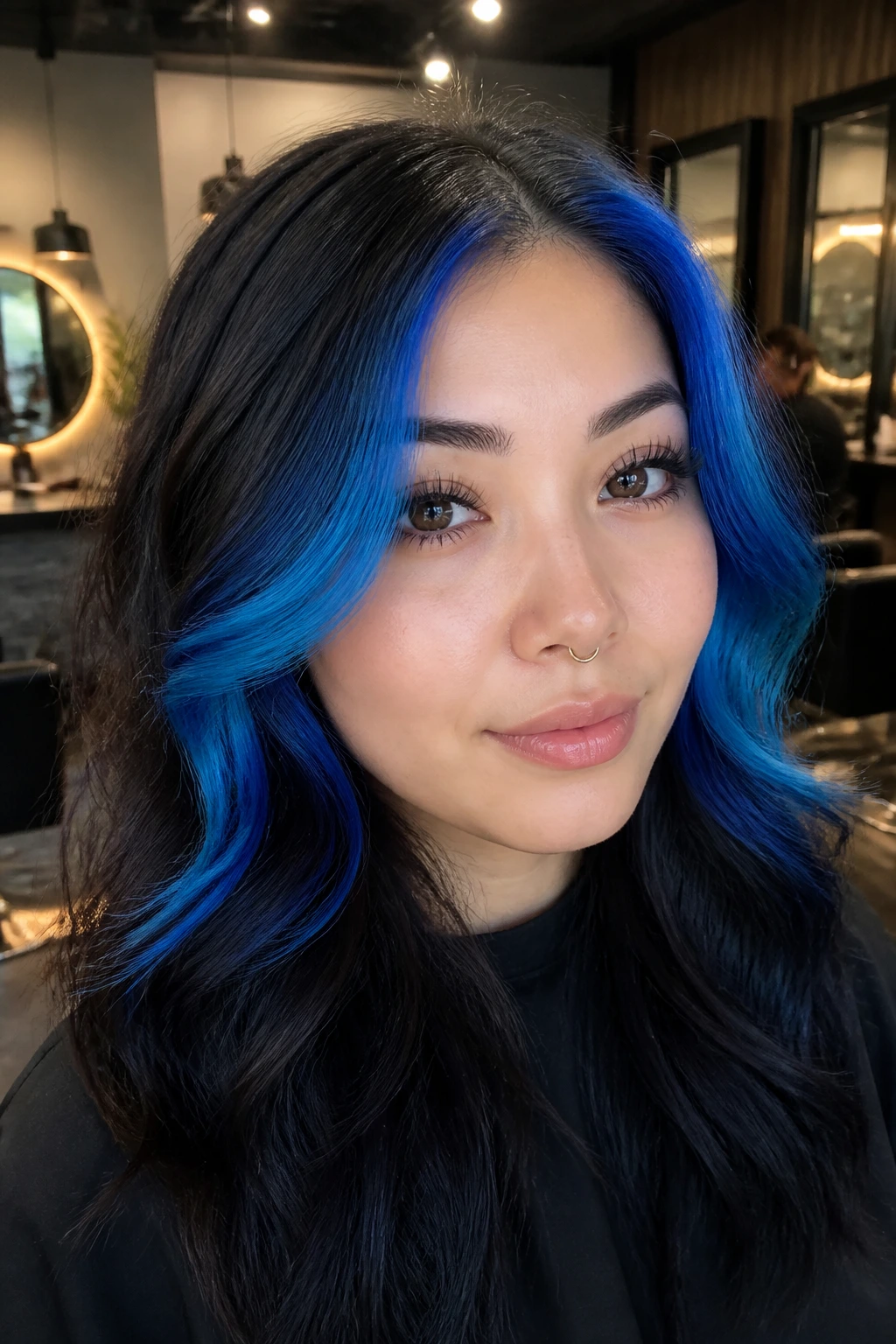 Portrait of a woman with electric blue money pieces framing the cheekbones against a dark base.