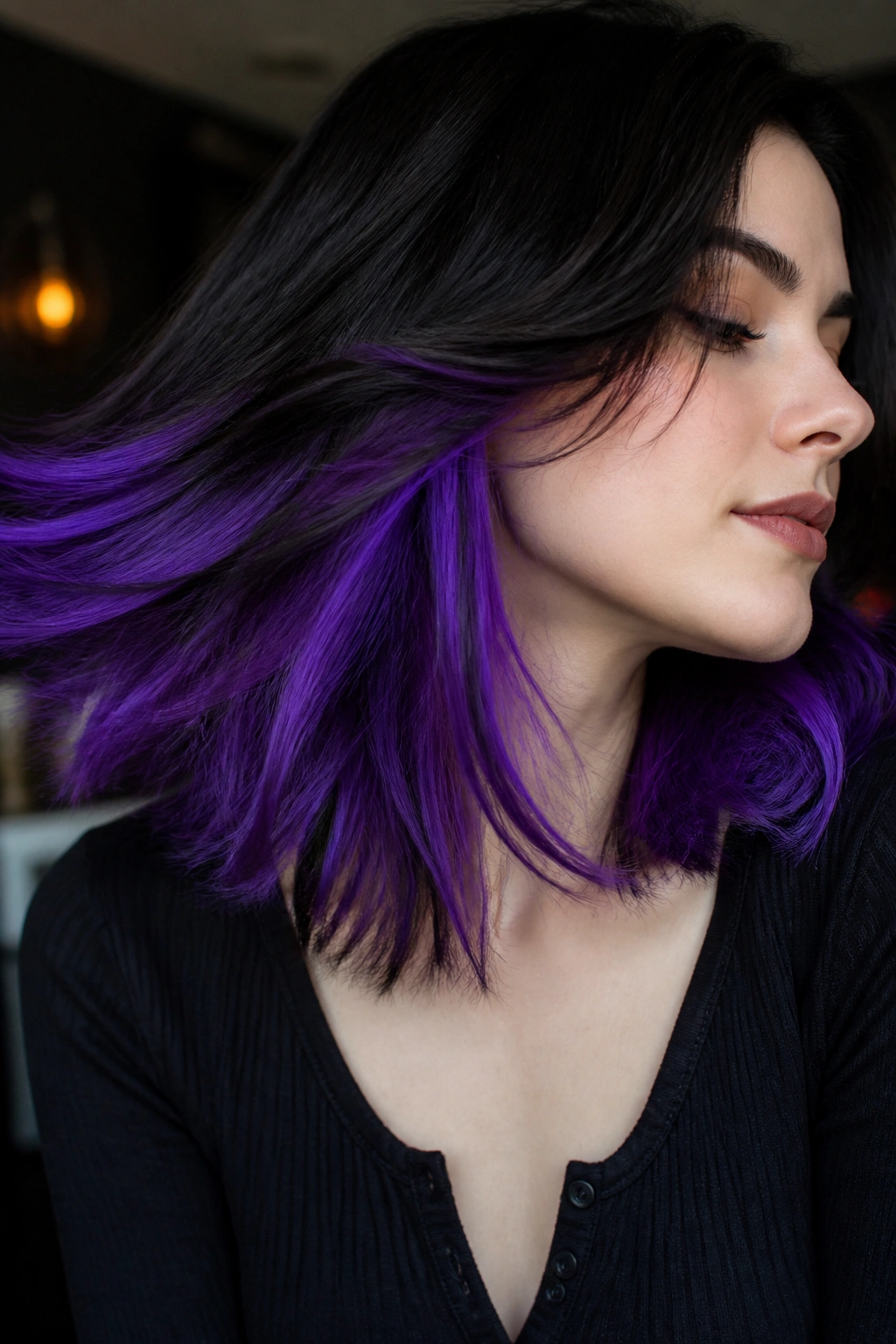 Close-up of a person with electric violet underlights peeking through dark hair