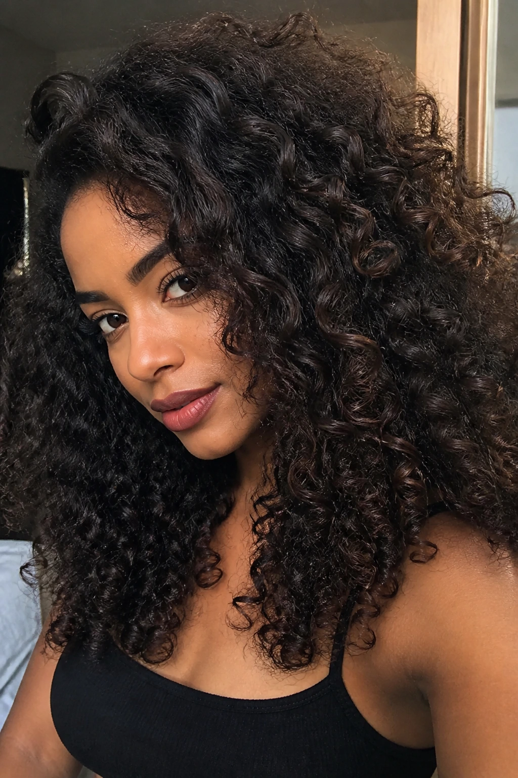 Close-up of a real person with espresso-black curls showing brown depth