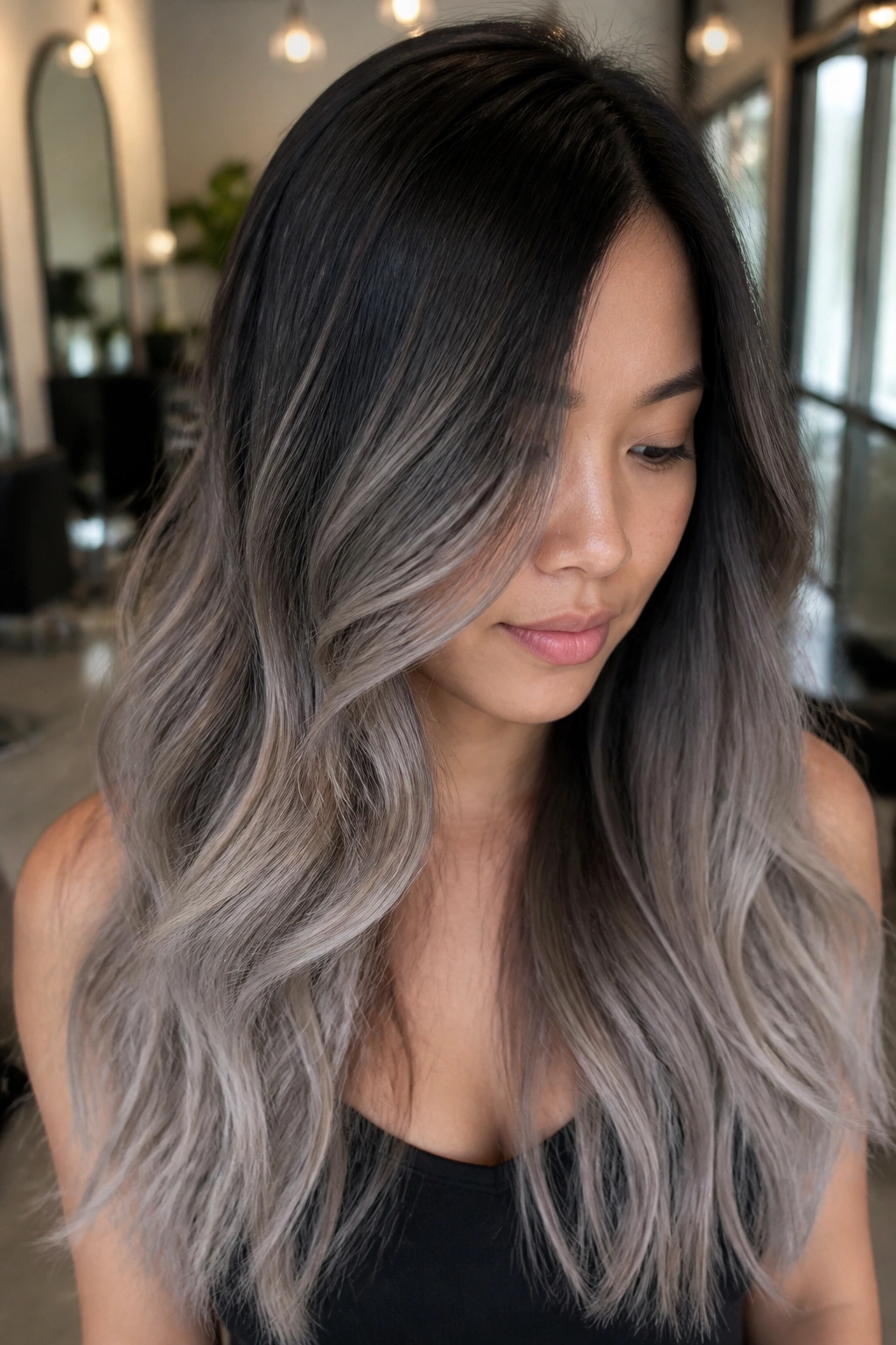 Close-up of a real woman with espresso roots and silver ash ends in long wavy hair.