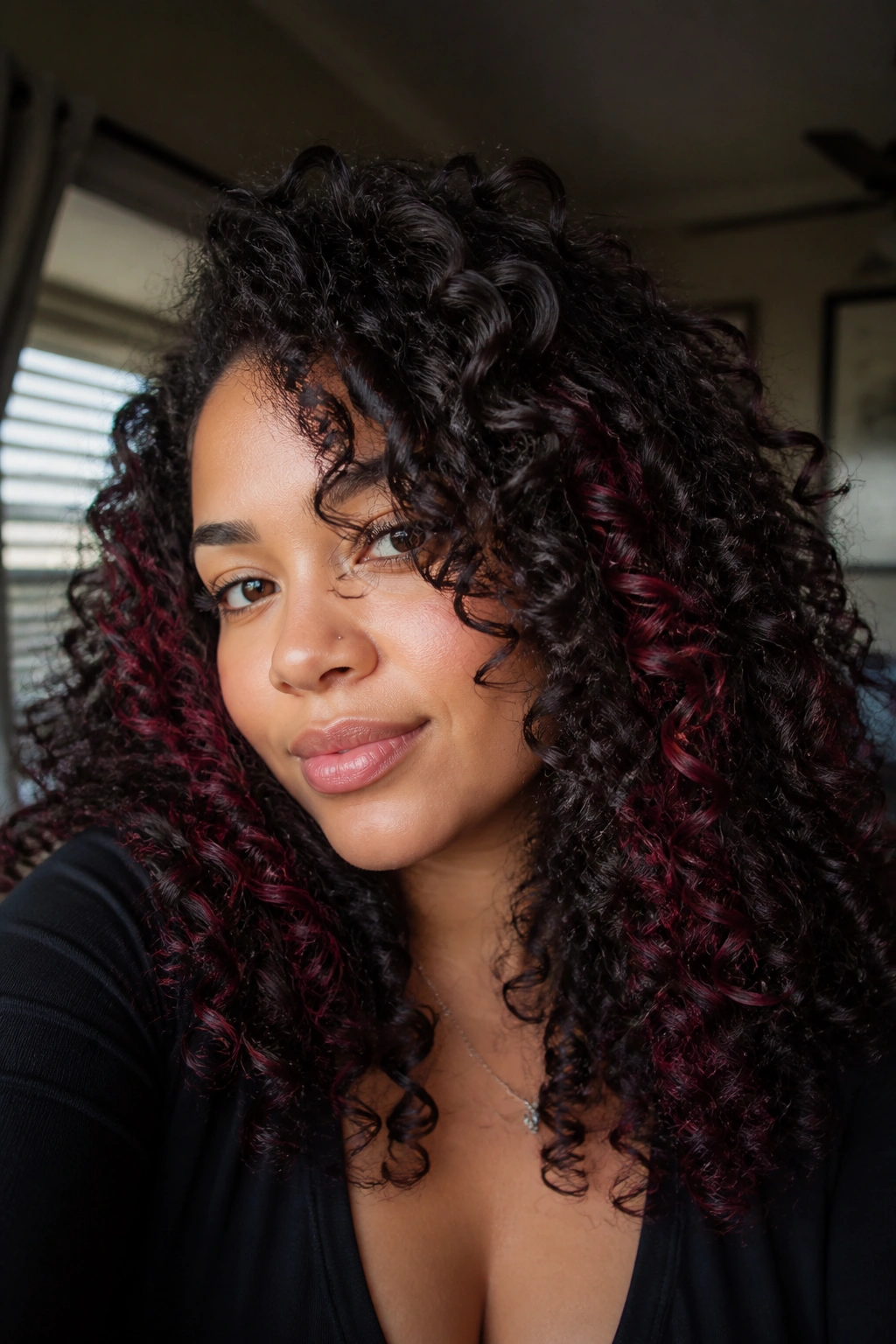 Close-up of real woman's curly hair with garnet peekaboo lows