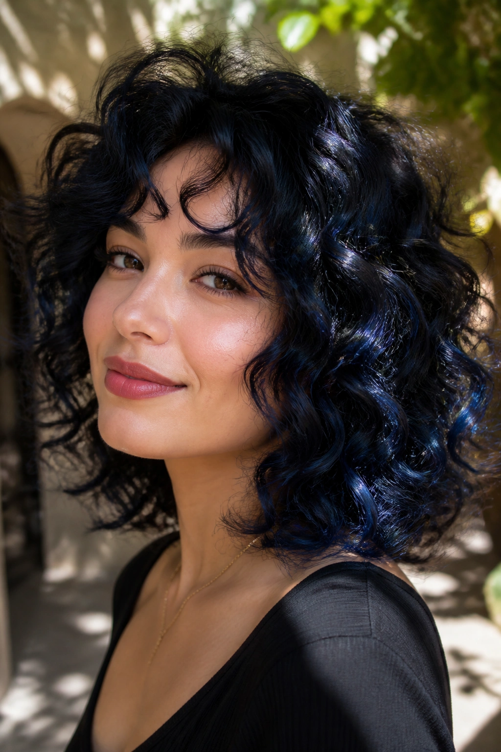 Close-up of a real person with curly blue-black hair featuring lighter outer curls