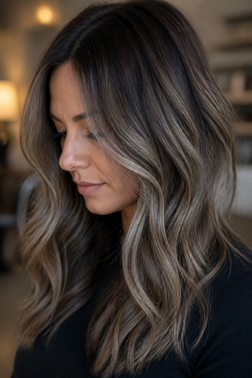 Close-up of a real woman with gray-beige balayage on brown hair in natural window light