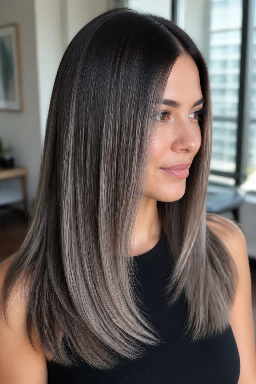 Close-up portrait of a woman with straight brown hair and gunmetal silver balayage