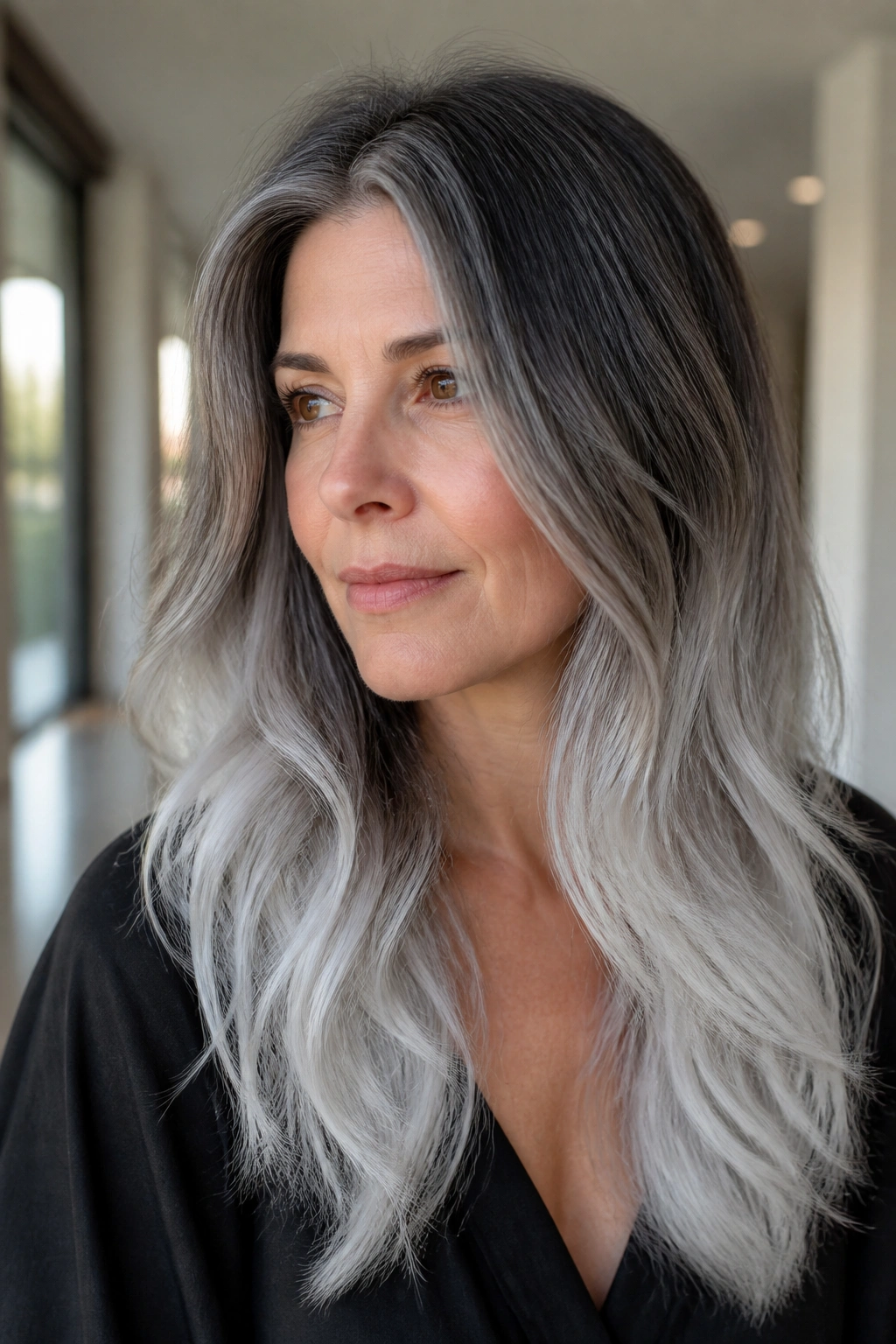 Close-up portrait of a real person with ice-gray ombré on long layered hair.