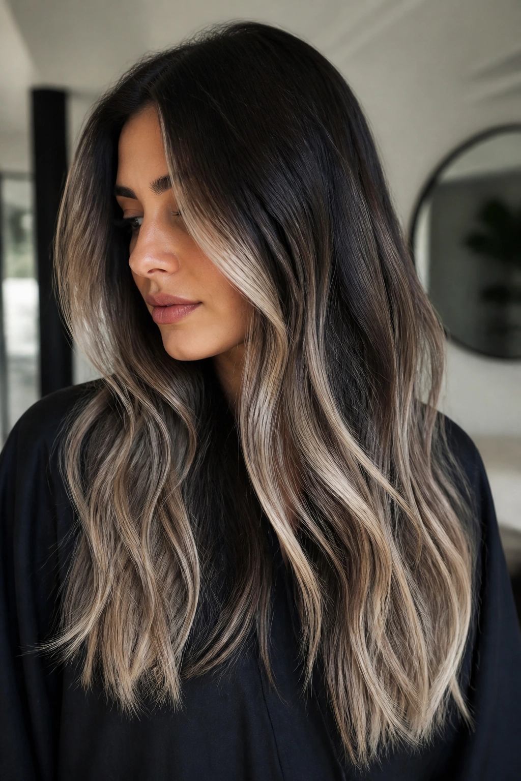 Close-up portrait of a real woman with icy beige balayage on deep brunette base under cool lighting.