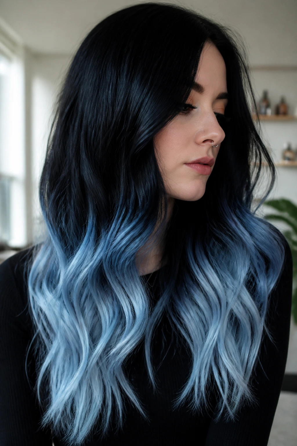 Close-up of a real woman with icy blue fade on jet black hair in a bright room.