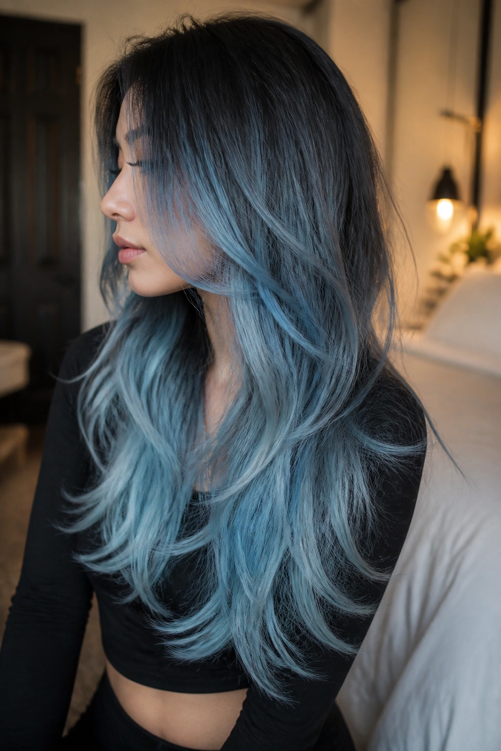 Side-profile of icy blue ombre with smoky charcoal root on long layered hair.