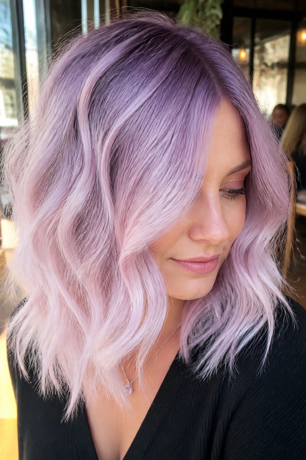 Close-up of a real woman with blue-based pastel lilac melt hair in cafe window light