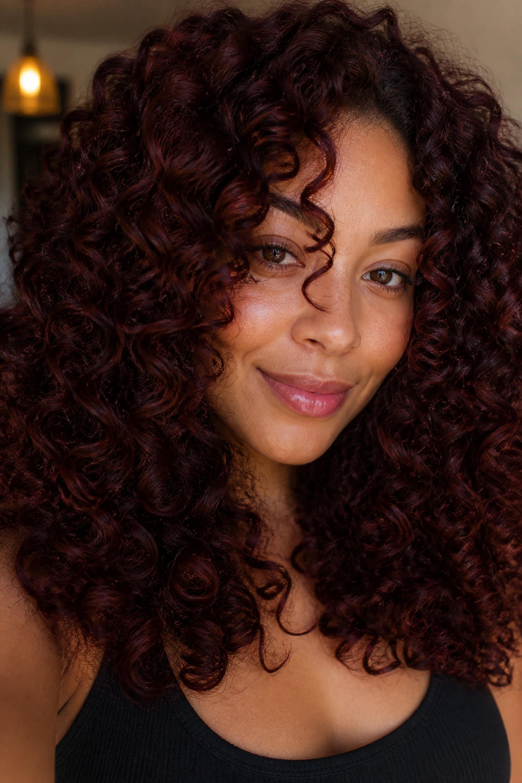 Close-up of real person with deep mahogany curls in red-brown wine tones
