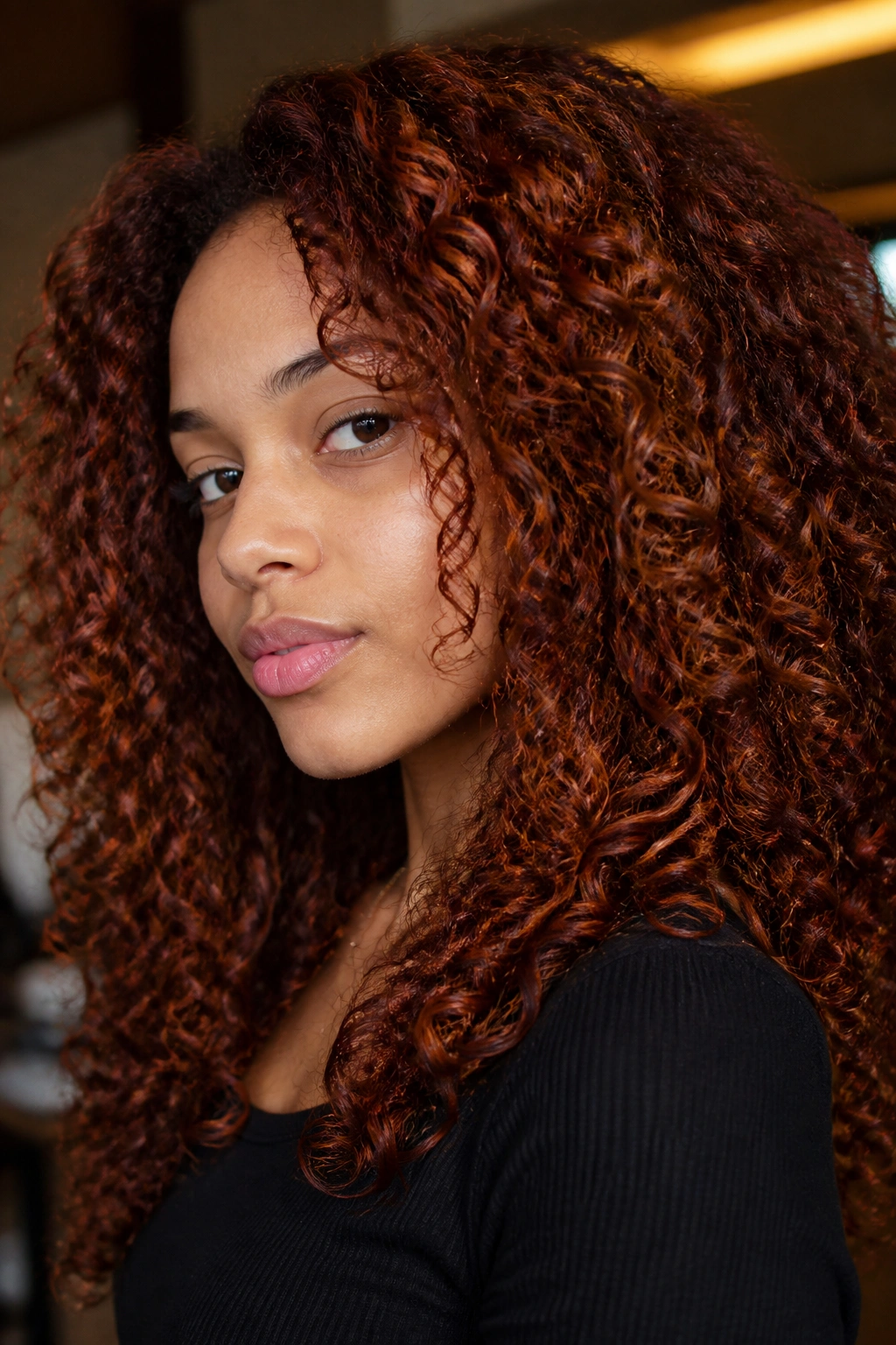 Close-up of a real person with mahogany ginger lowlights in curly hair