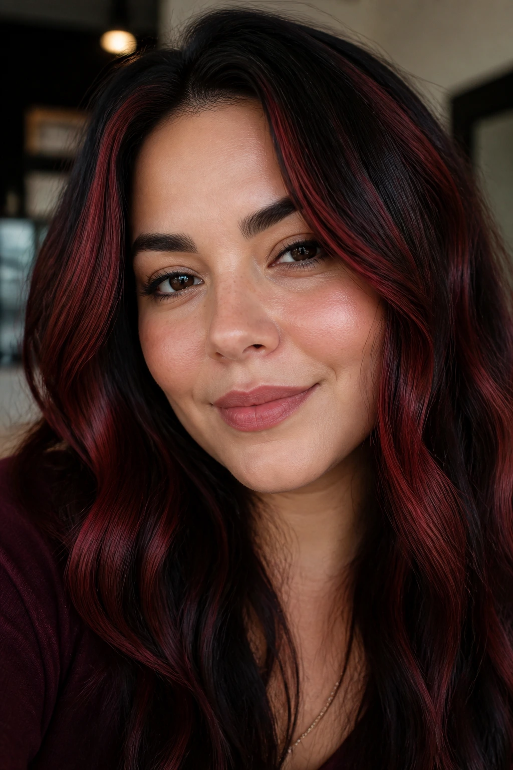Close-up portrait of a woman with mahogany lowlights and red highlights.