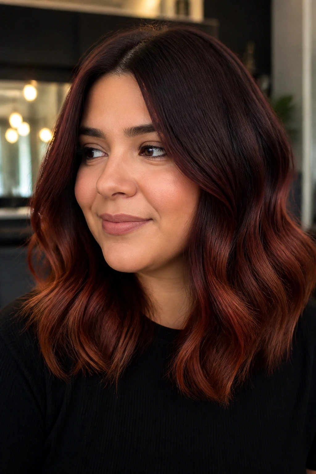 Close-up portrait of a real woman with deep mahogany roots fading to warm ends
