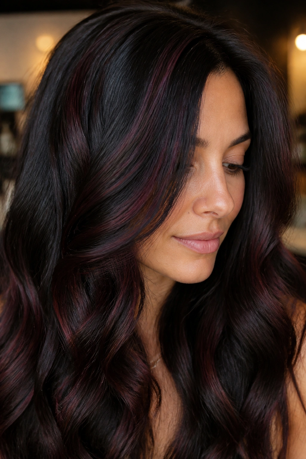 Close-up of brunette hair with deep merlot-mahogany lowlights visible under light