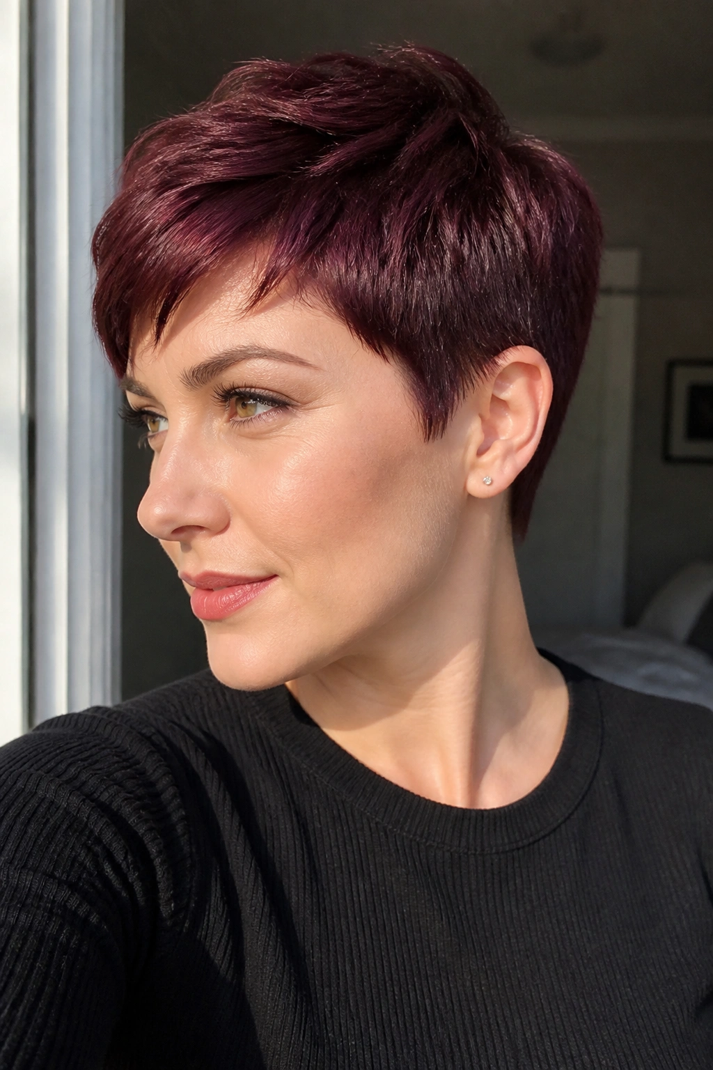 Close-up of a real woman with a merlot pixie crop, glossy short burgundy hair