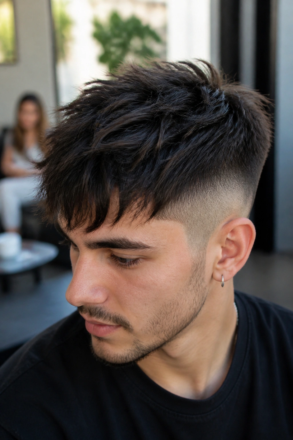 Close-up portrait of a man with a messy fringe undercut in a bright cafe