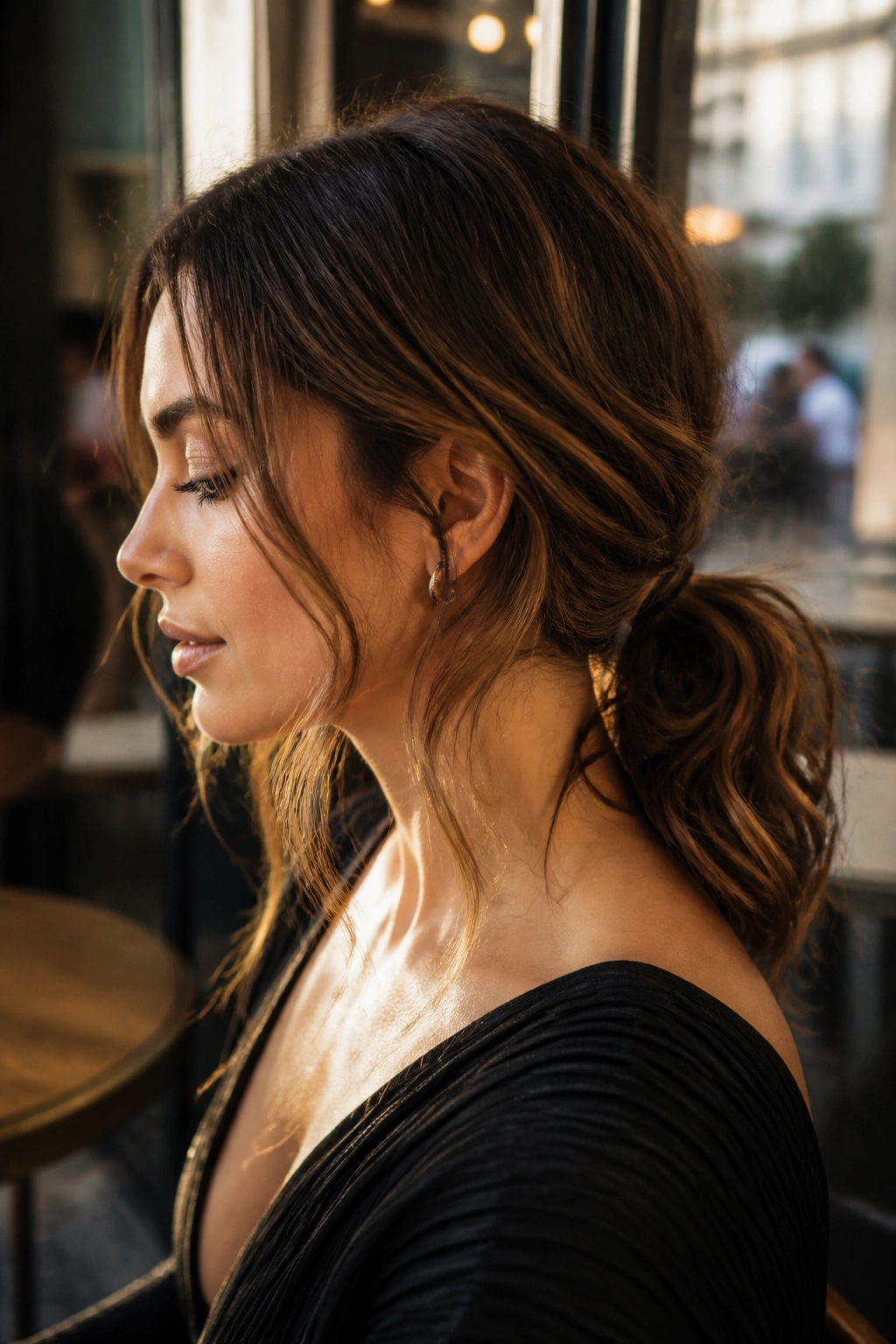 Portrait of a real woman with a messy low ponytail and soft waves at the nape.