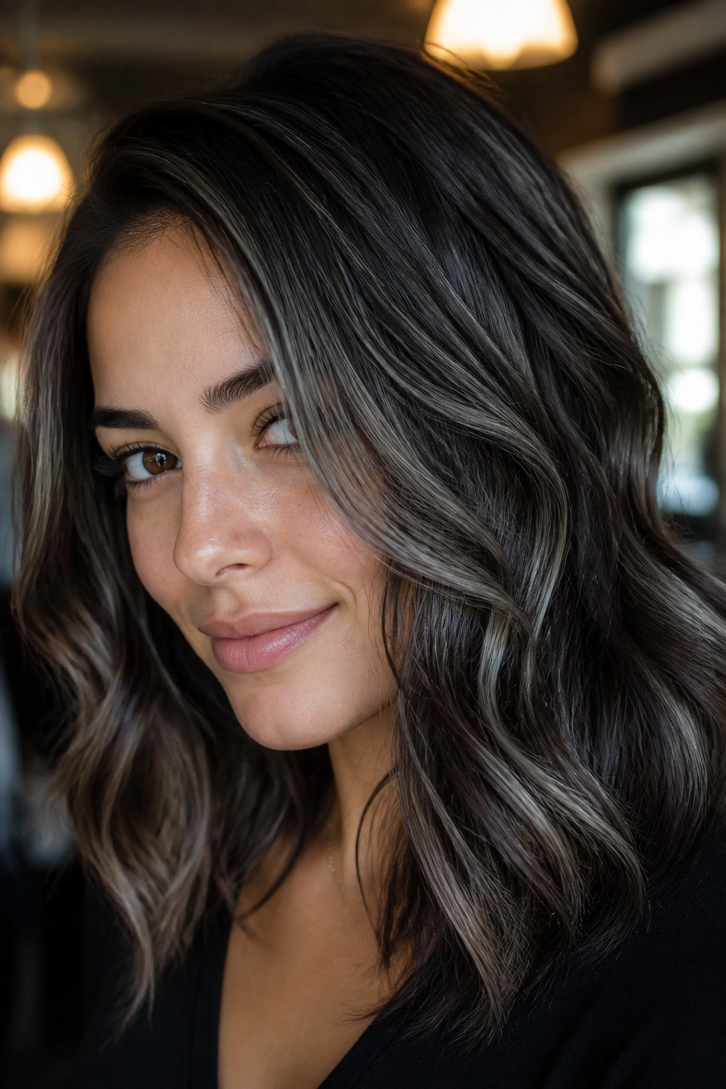 Close-up of dark brunette hair with metallic grey highlights catching light