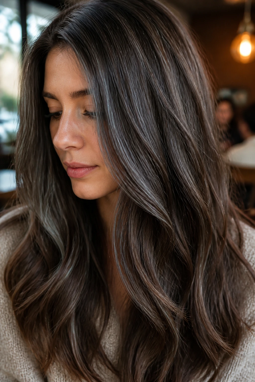 Close-up of brunette with cool cocoa micro-lights in warm cafe light.