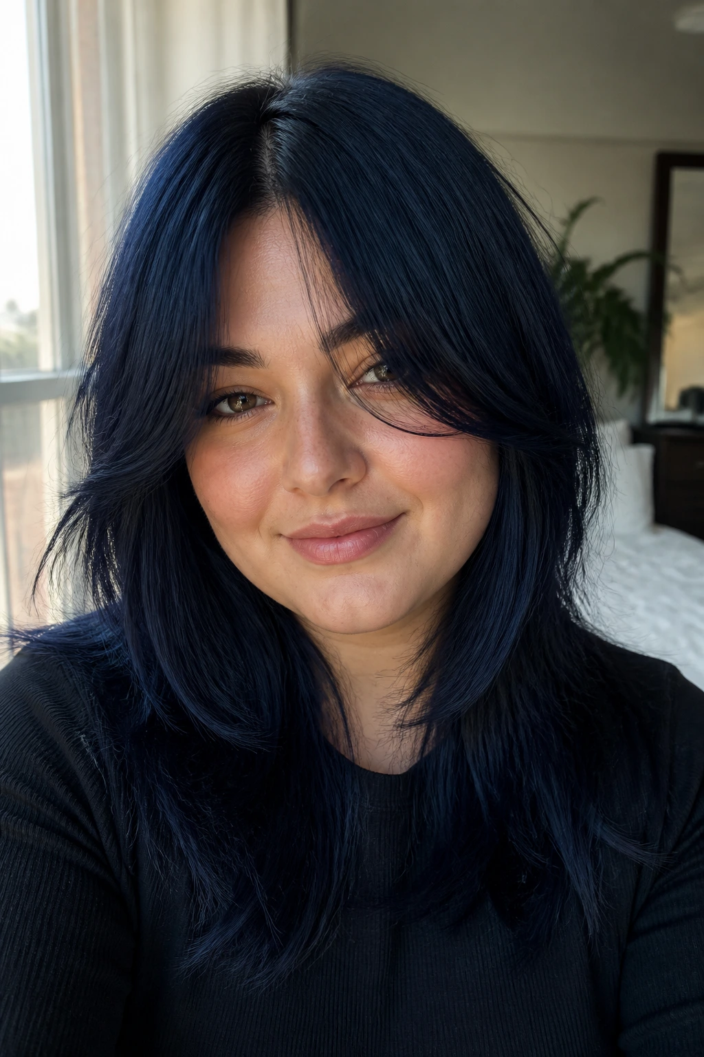 Portrait of a woman with midnight blue curtain bangs framing the face.