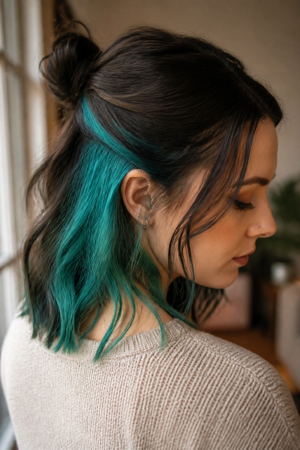 Close-up portrait of a real woman with a mint-teal underlayer peeking from a darker top layer in a half-up hairstyle