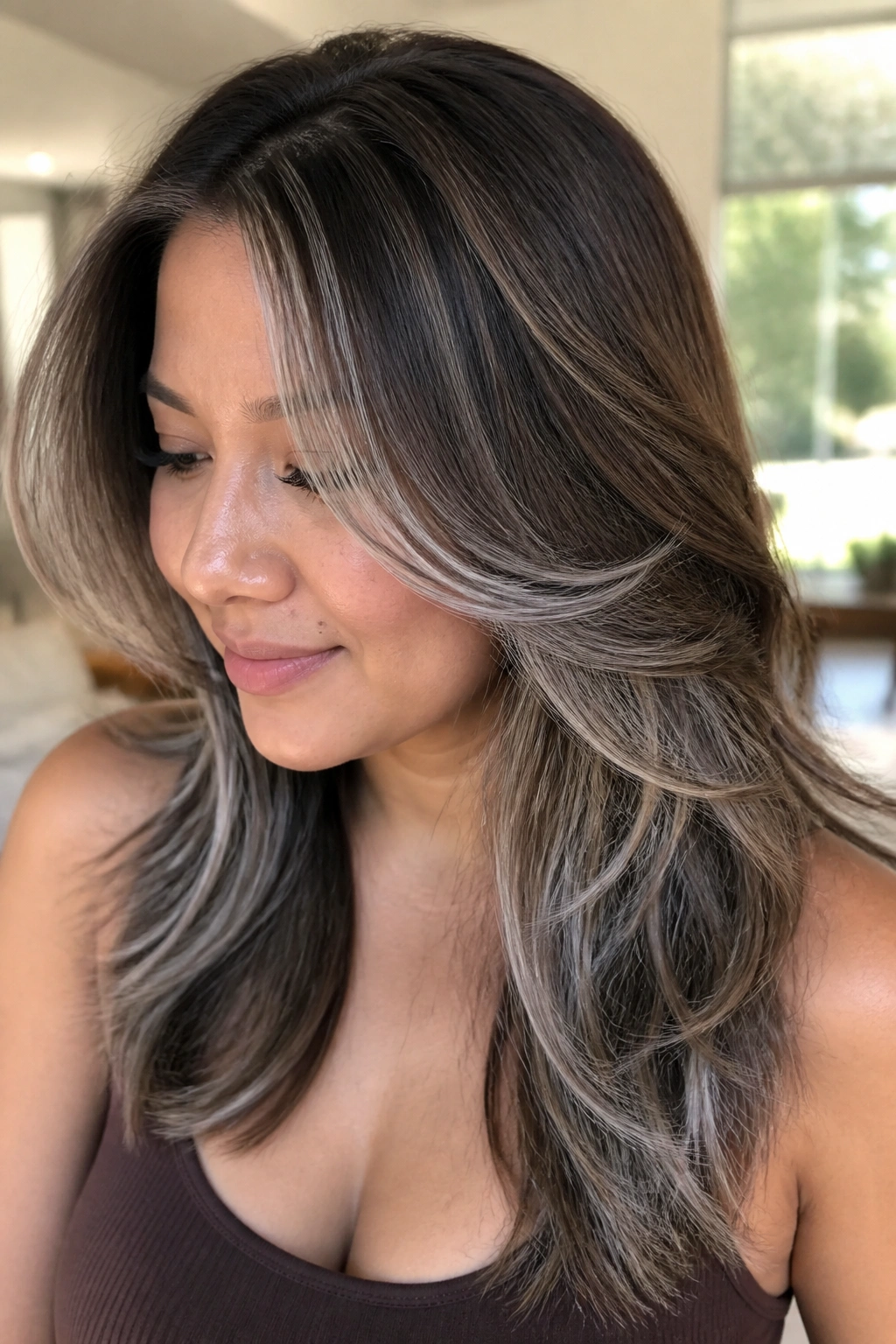 Close-up of a real woman with mocha brown hair and feathered silver ribbons along the layers.