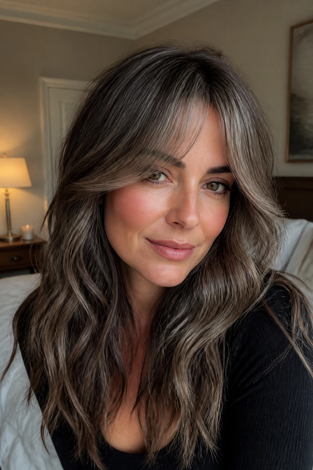 Close-up portrait of a real woman with mushroom balayage and smoky curtain bangs in warm window light