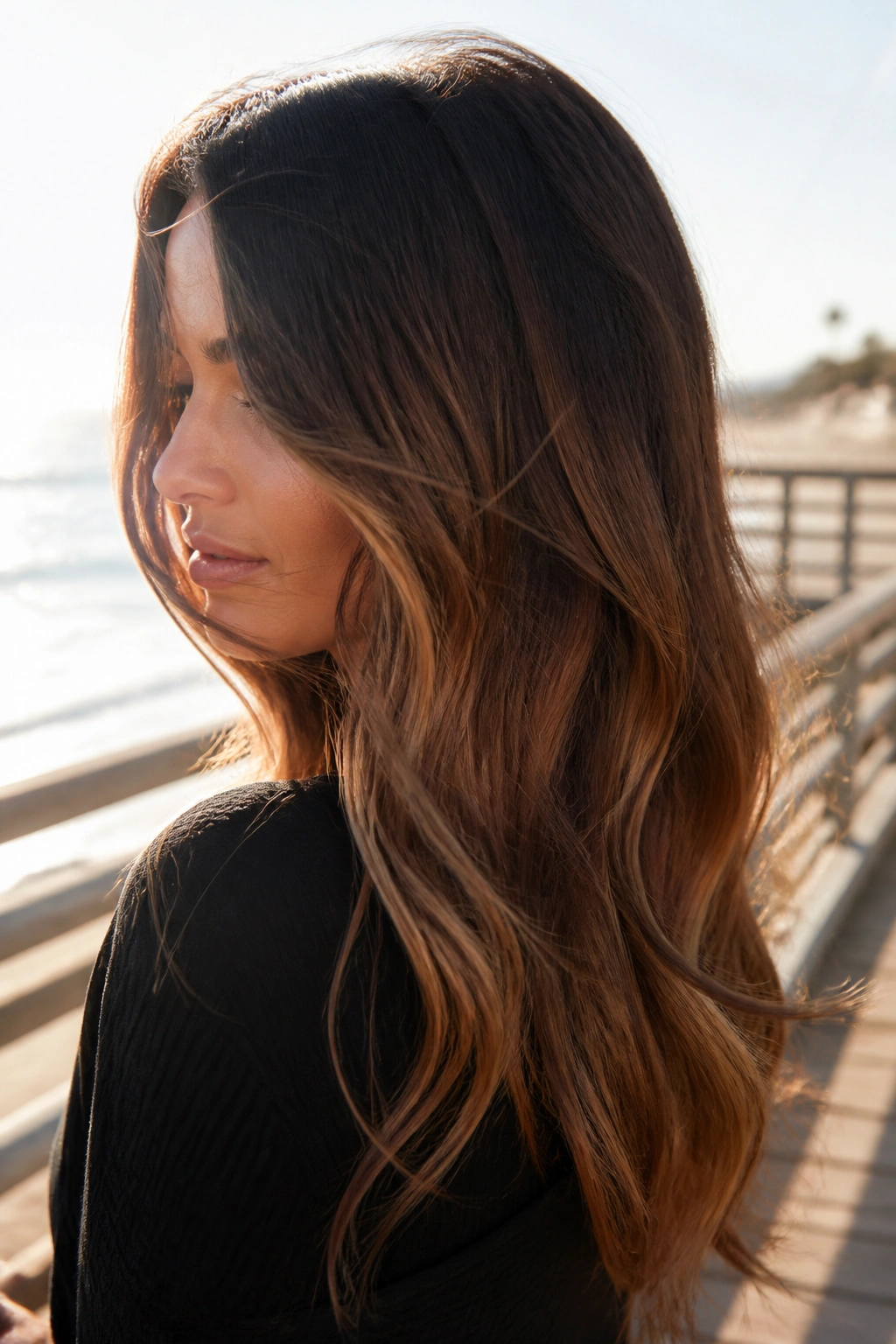 Close-up of a real woman with brunette ombré from dark roots to warm cocoa ends at sunset.