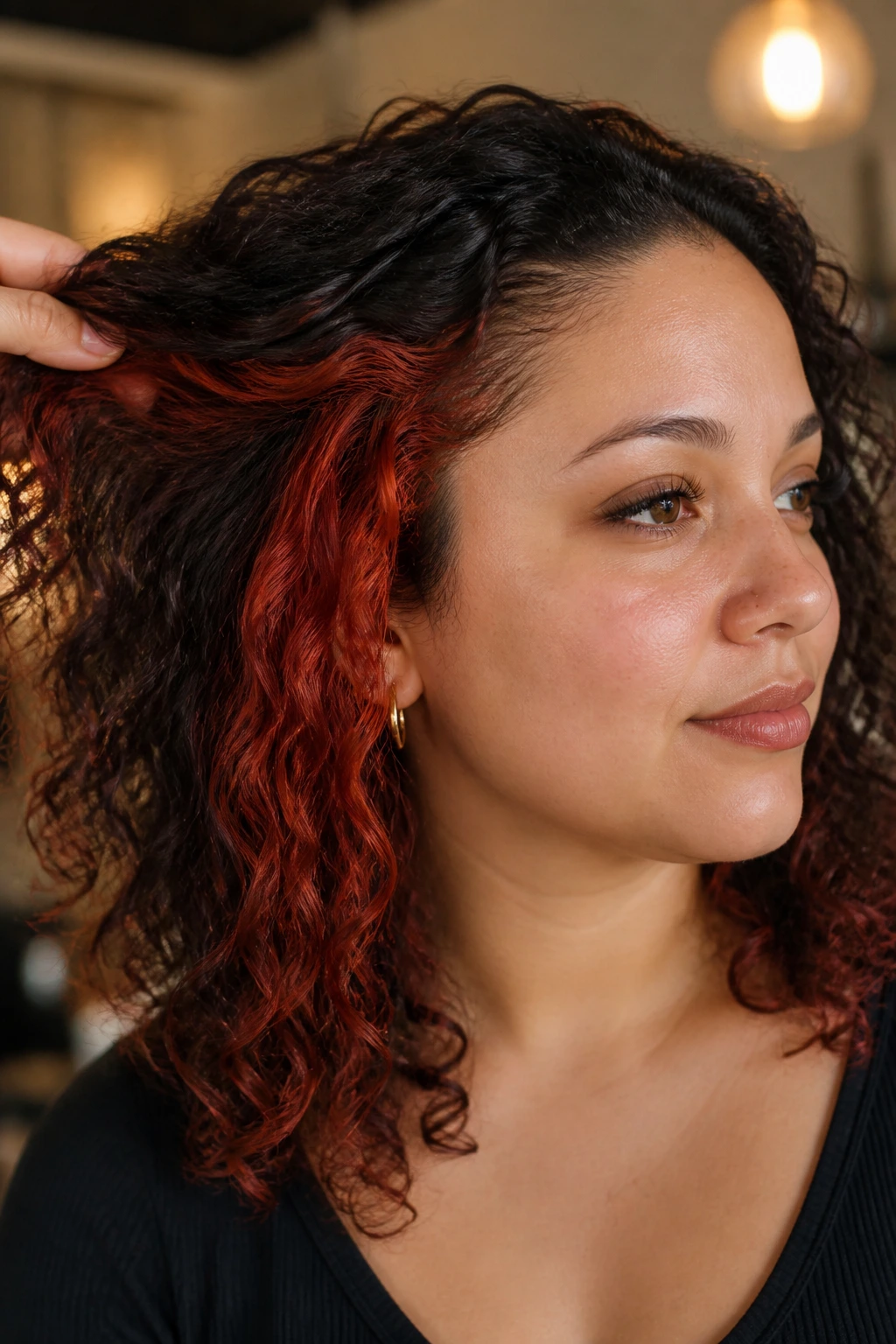 Close-up of paprika red peekaboo panels under dark curls on a real woman