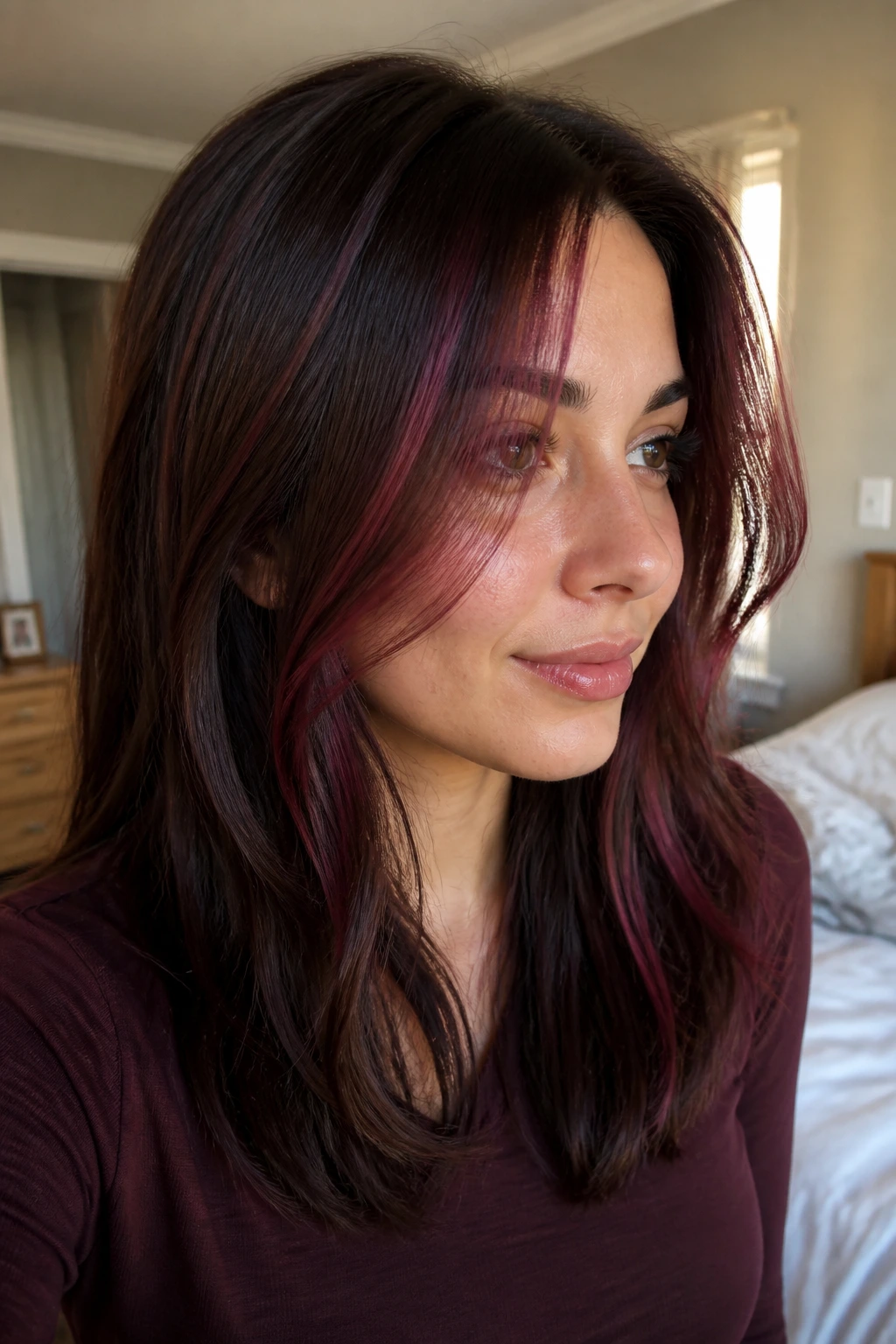 Close-up portrait of a real woman showing partial burgundy pink highlights around the face on brown hair