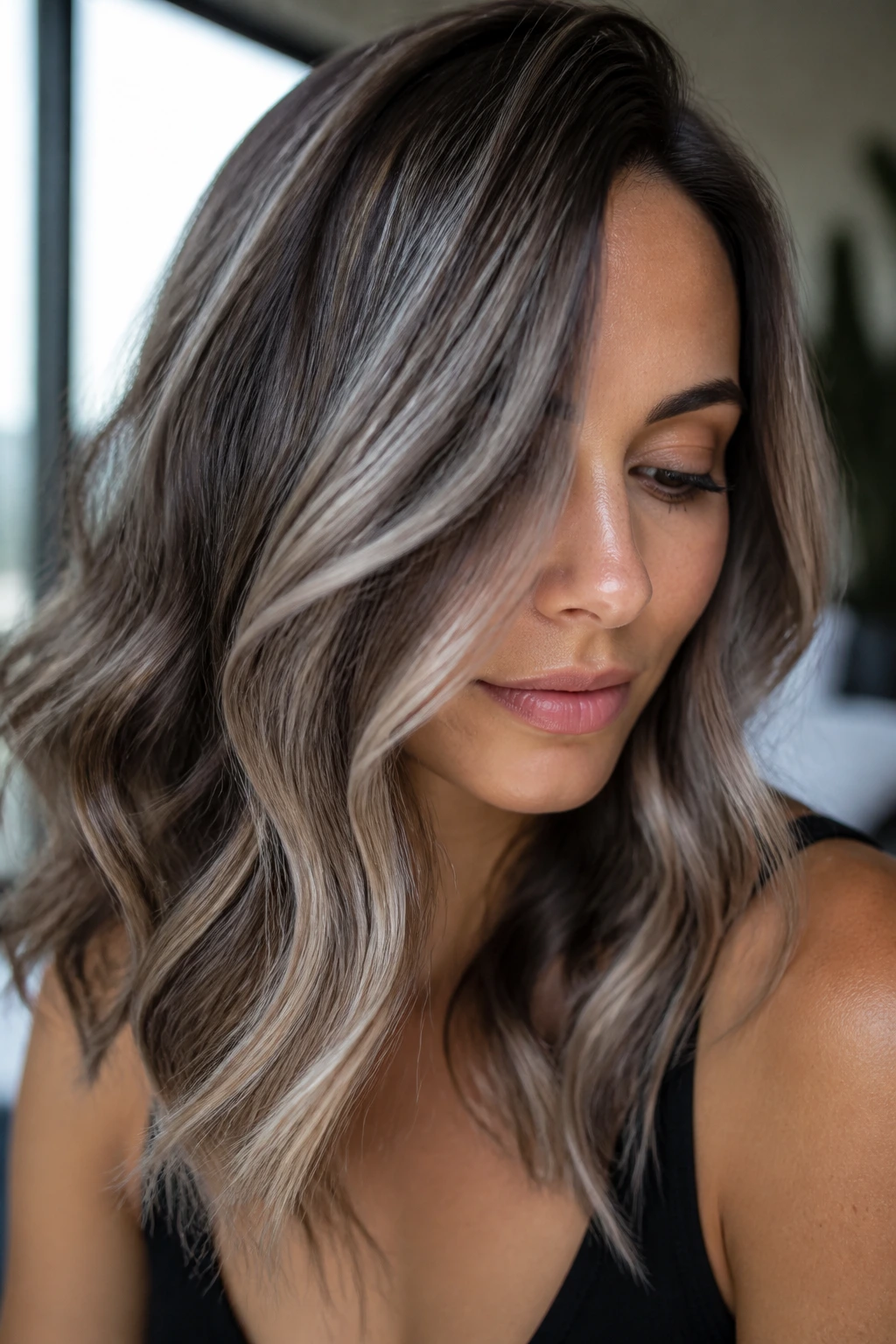 Close-up portrait of a real woman with pearl-grey glossed highlights on brunette hair