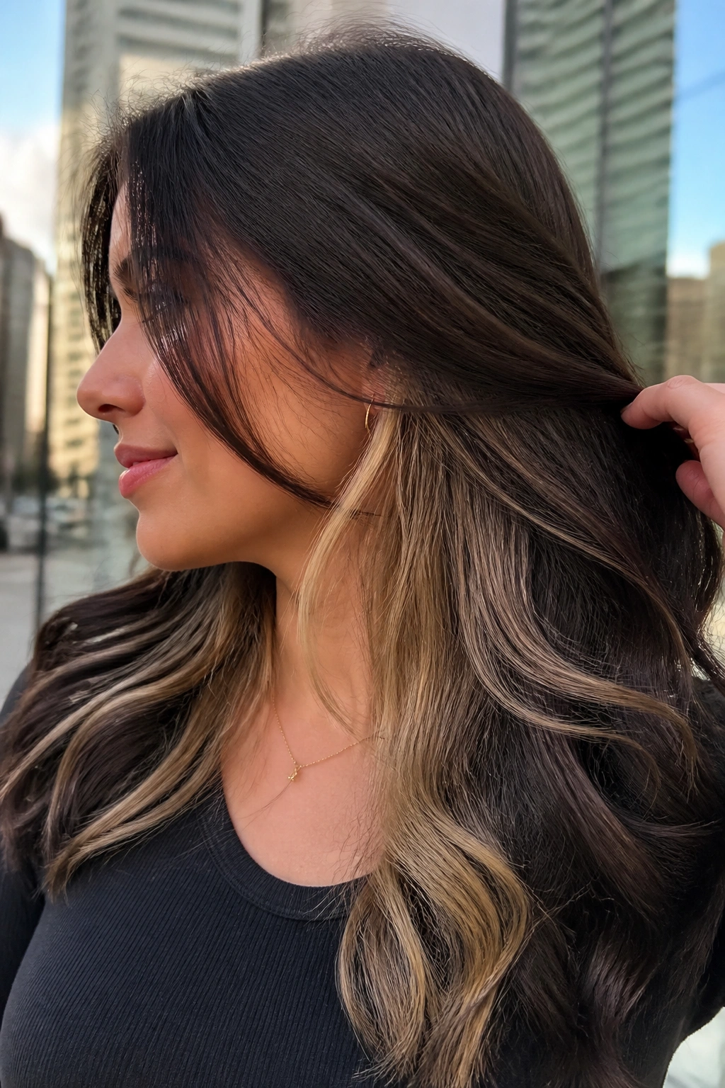 Close-up of a real woman showing peekaboo blonde underlayers beneath dark top layer