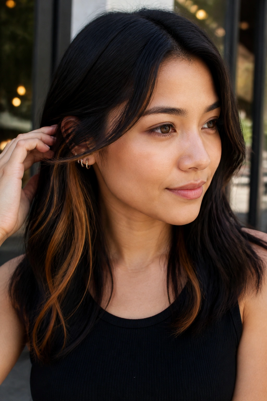 Portrait of a real woman showing hidden caramel underlayers behind the ear.