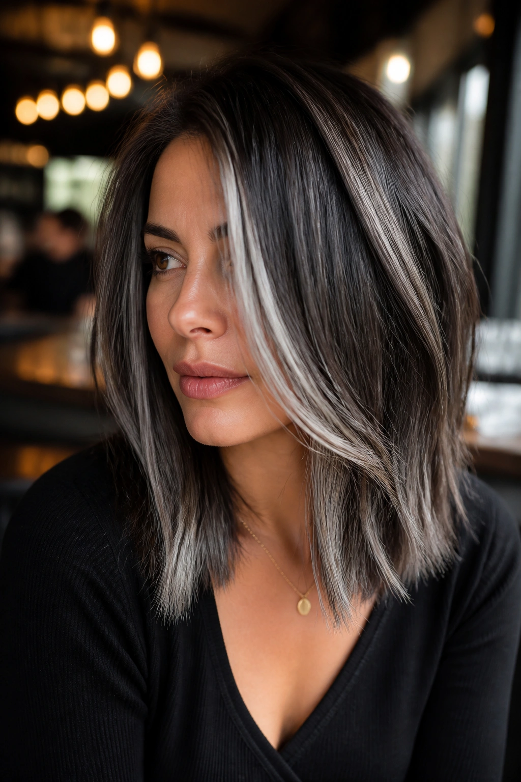 Close-up of a real woman with bold pepper panels on deep brunette hair
