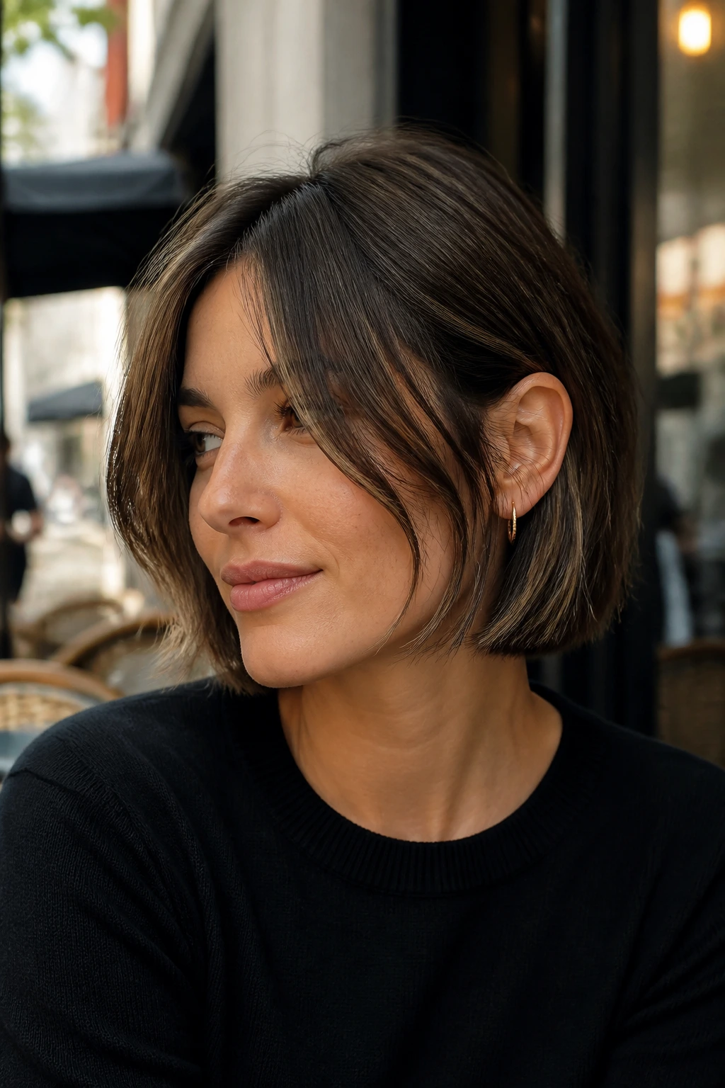 Portrait of a woman with piecey face-framing French bob tucked behind one ear