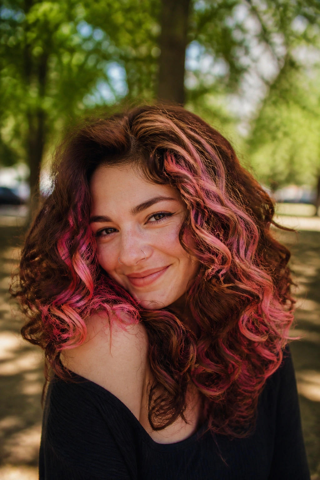 Close-up of a real woman with curly brown hair showing pink chunky highlights along curls
