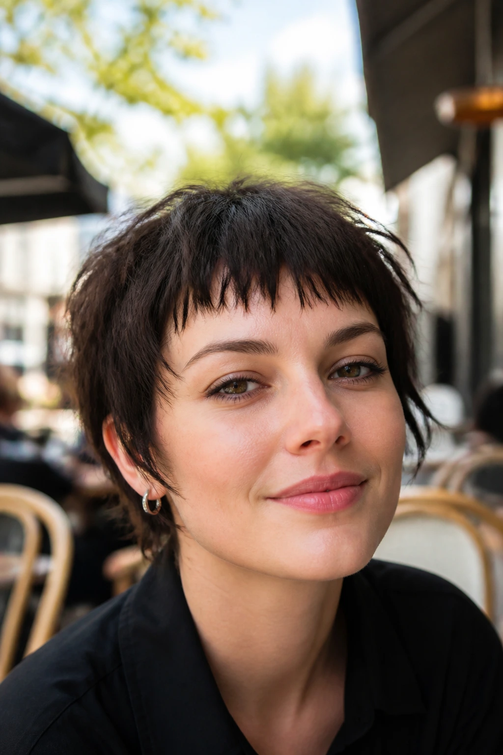Portrait of woman with wispy micro-bangs pixie in sunlit cafe