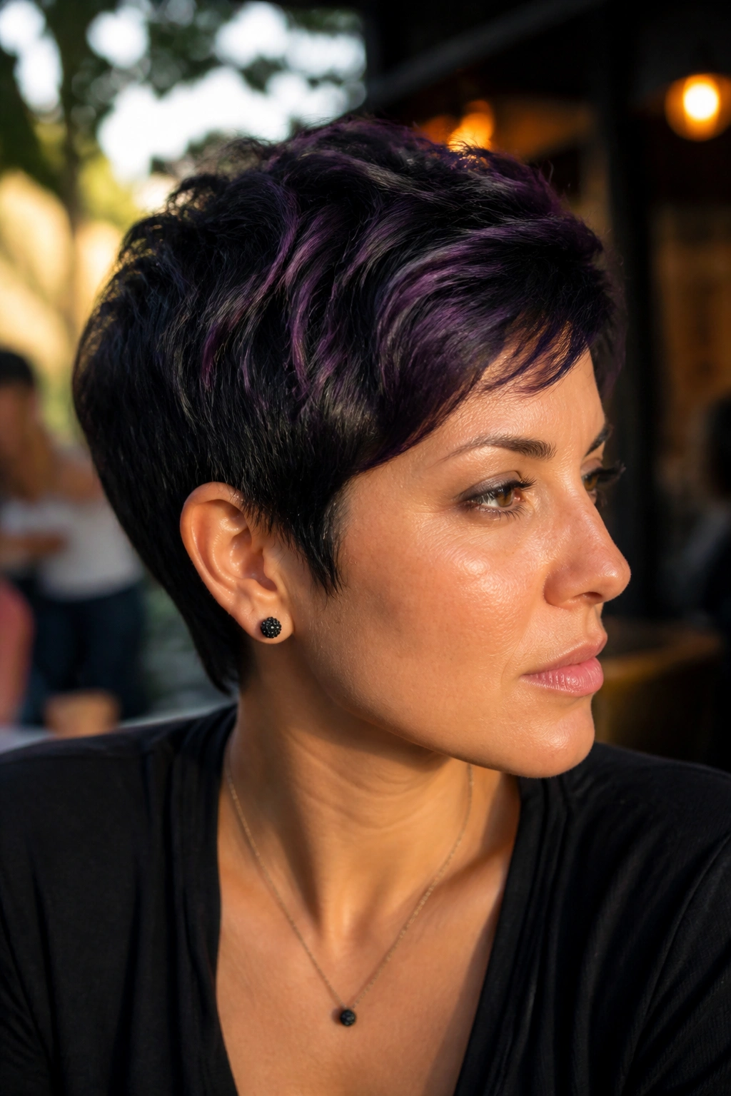 Close-up portrait of a real person with a black pixie and purple micro highlights outdoors at golden hour