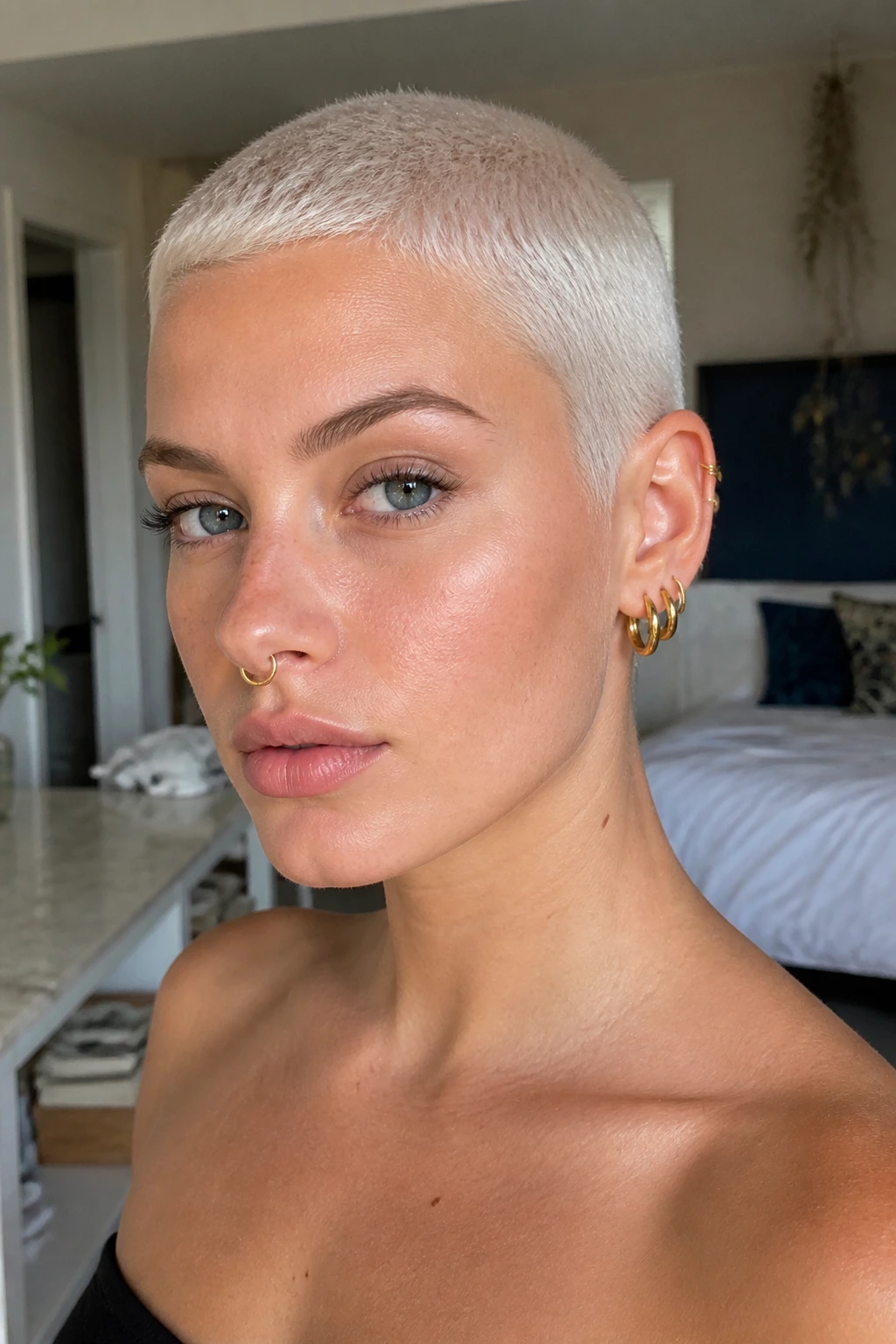 Close-up portrait of a real person with a platinum buzz cut in a modern interior.