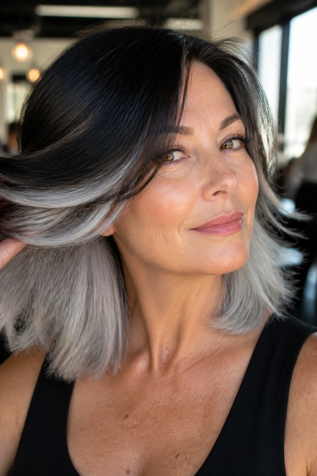 Close-up of a real woman showing platinum-gray underlights beneath a darker top layer