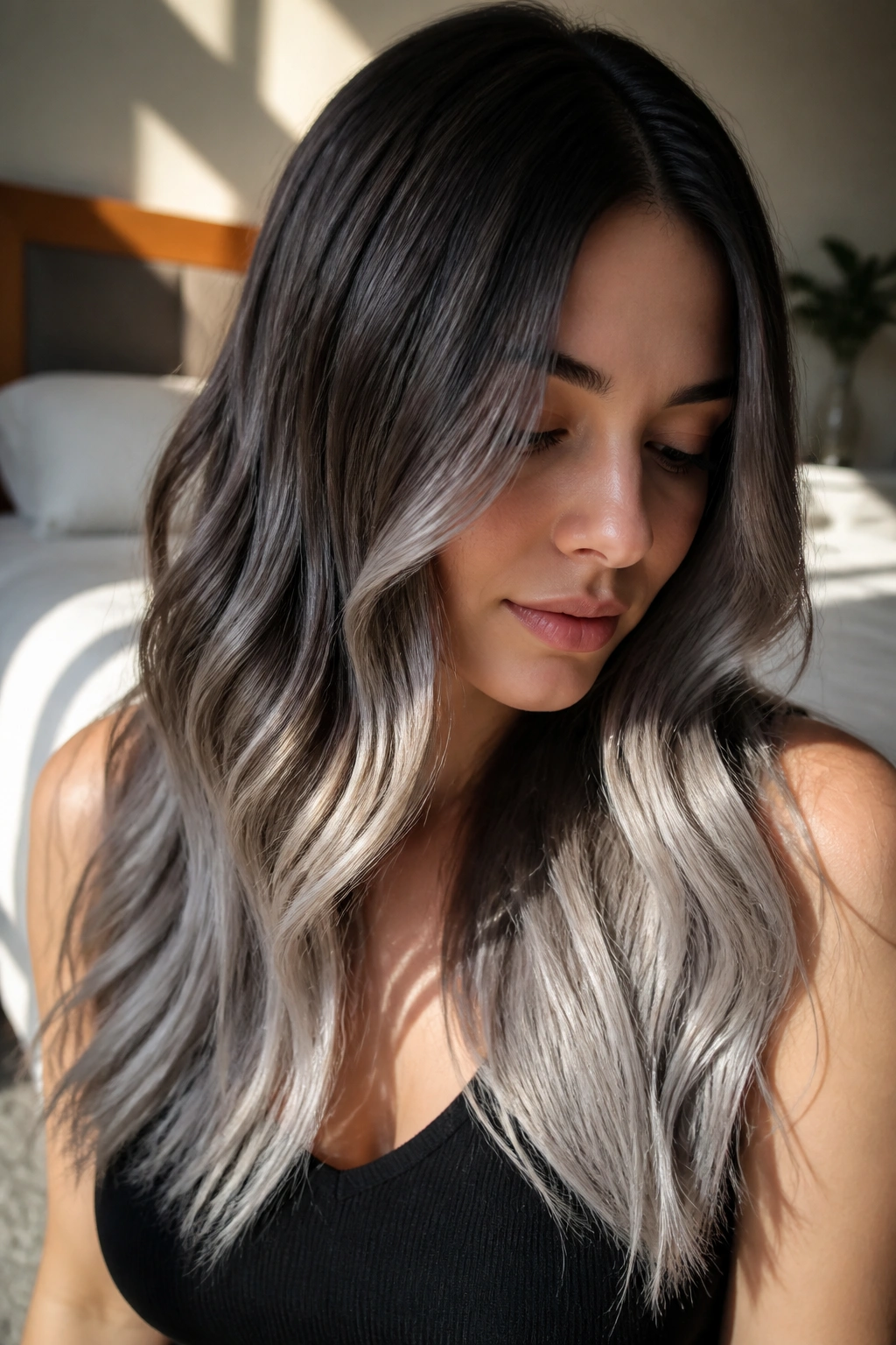 Close-up of a real woman's long hair with brunette roots fading into platinum silver ends brushed into soft waves.
