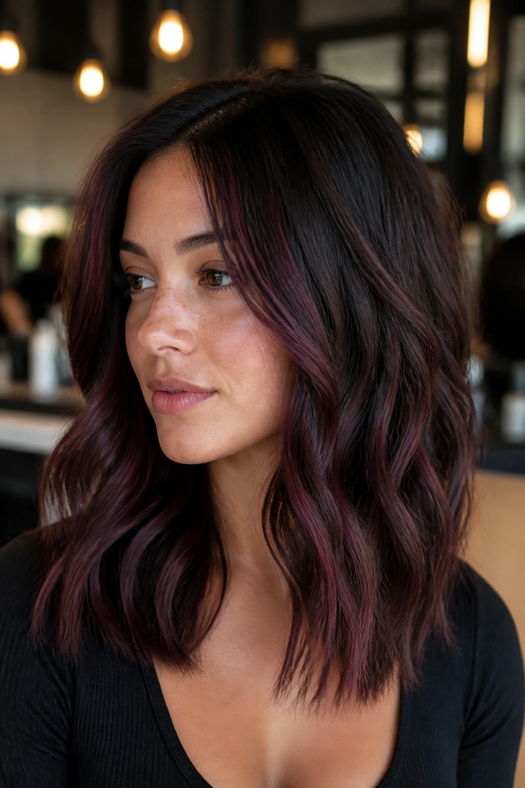 Close-up of a real woman with plum-brown balayage on dark brunette hair framing the face