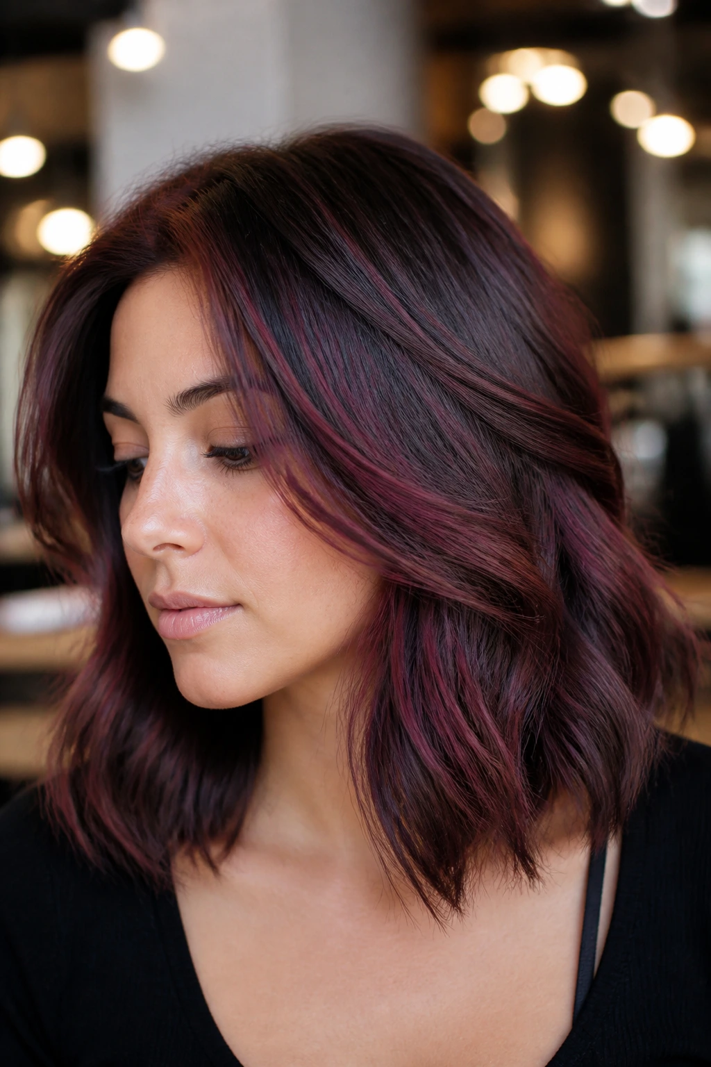 Shoulder-length hair with plum lowlights and burgundy highlights in a warm salon