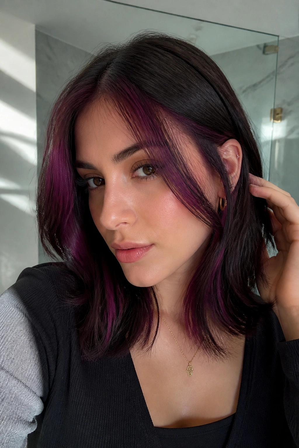 Close-up of a real woman with a deep plum money piece at the hairline.