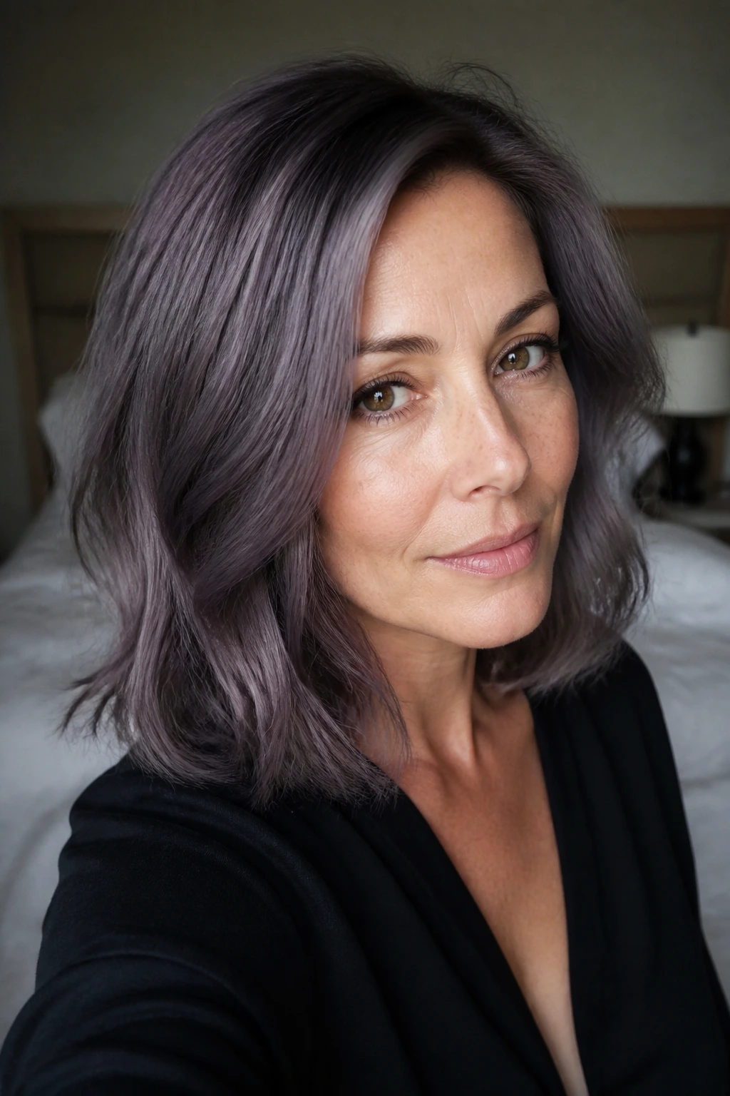 Close-up of a real woman with shoulder-length hair in smoky grape gloss purple-grey, natural window light.