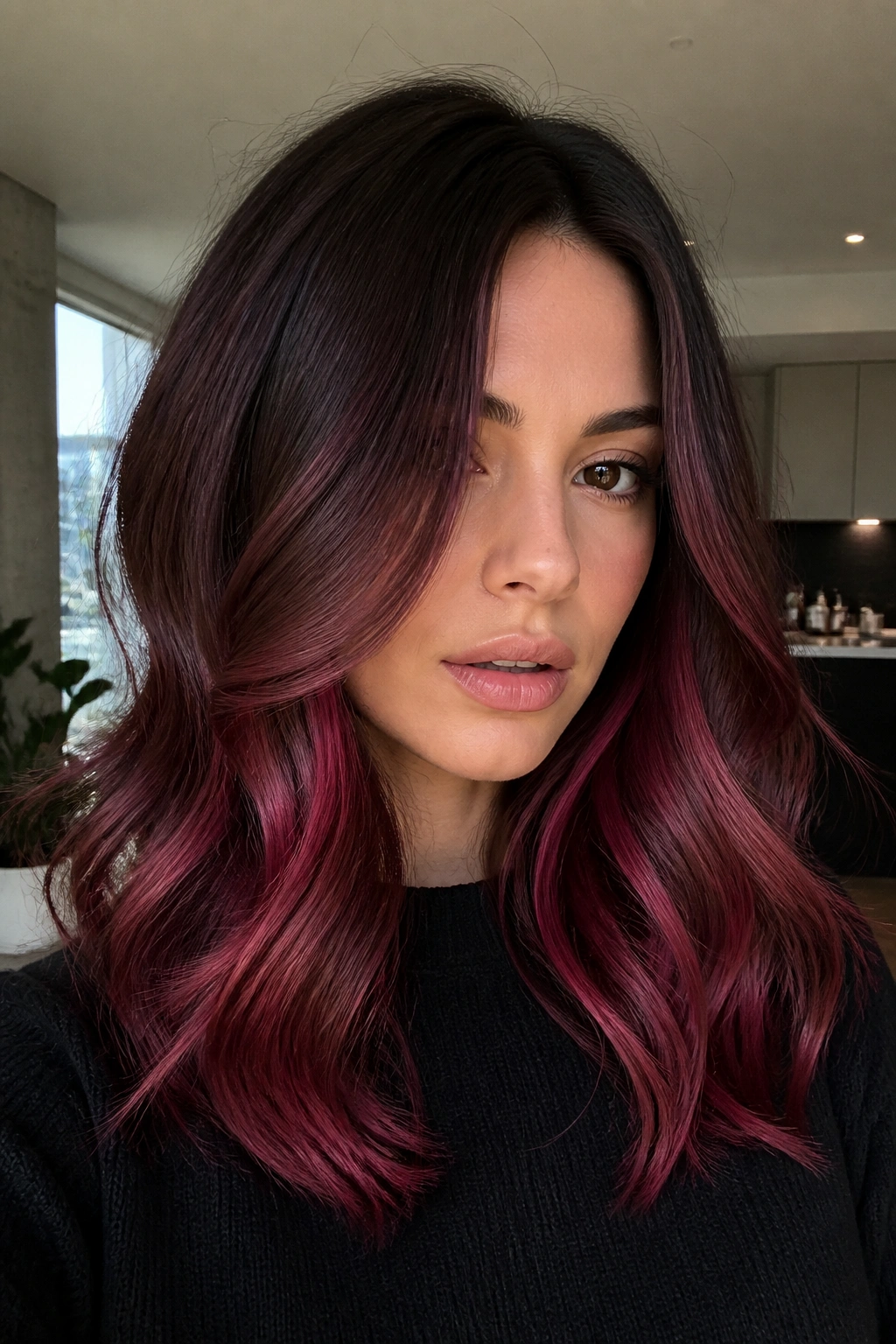 Close-up portrait of a real person with raspberry brown balayage on brunette hair.